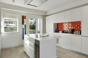 a kitchen with white cabinets and a red brick wall at Bright & Modern Townhouse Private Parking in Saint Columb Minor