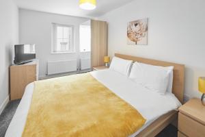 a bedroom with a large bed with a yellow blanket on it at Skinningrove Apartment six in Skinningrove