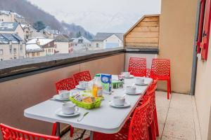 a table on a balcony with red chairs at Appartement Bois de Marie in Sers