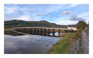 a bridge over a river with mountains in the background at The Moorings in Fairbourne