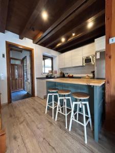 a kitchen with two bar stools and a blue island at Chalet con encanto Jardín y Parking Privado in Vielha
