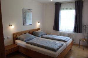 two beds in a bedroom with a window at Ferienhaus Nr 57, Kategorie Königscard, Feriendorf Hochbergle, Allgäu in Bichel +10 photos