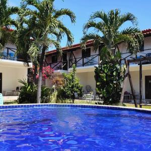 una piscina di fronte a un edificio con palme di Bangalô 7 Carapibus a Conde