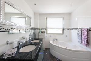 a bathroom with two sinks and a tub and a large mirror at Penthouse für 2 Personen mit Dachterrasse und Rheinblick in Patersberg