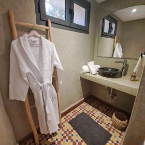 a bathroom with a sink and a towel hanging on a chair at Villa 15 personnes avec piscine in Sidi Kaouki