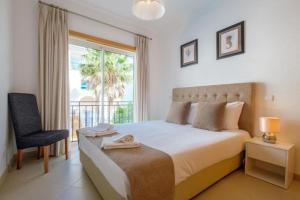 a bedroom with a bed and a chair and a window at Praia D'el Rey A1 - Golf & Beach in Óbidos