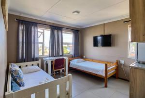 een hotelkamer met twee bedden en een tv bij Ballito Backpackers in Ballito +40 foto's
