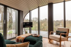 a living room with large windows and a tv at Sustainable 2 Bedroom Pod on Old Chalford Farm! in Enstone