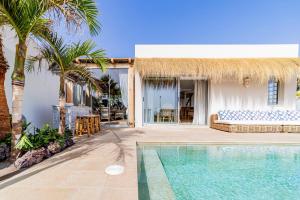 a villa with a swimming pool and palm trees at Ixchel Beach House By Sunkeyrents in El Médano