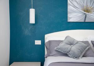 サンタ・ヴェネリーナにあるLa Rosa dell'Etna - Apartmentsのベッドルーム1室(青い壁の白いベッド1台付)