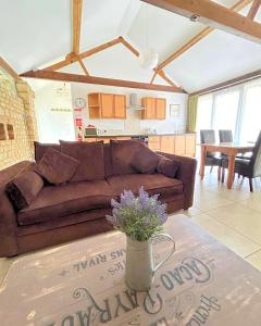 ein Wohnzimmer mit einem braunen Sofa und einem Tisch in der Unterkunft Partridge Place at Tove Valley Cottages in Towcester