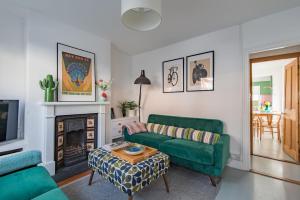 a living room with a green couch and a fireplace at Fern Cottage by Keepers Cottages in Whitstable