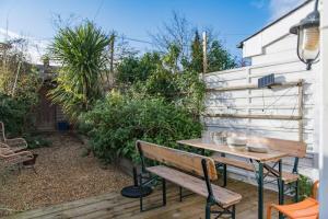 a patio with a wooden bench and a table at Fern Cottage by Keepers Cottages in Whitstable