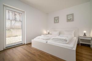 une chambre blanche avec un grand lit blanc et une fenêtre dans l'établissement Ferienhaus-Schilfblick, à Buchholz