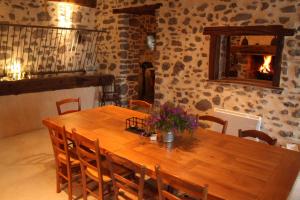 einen Holztisch und Stühle in einem Zimmer mit Kamin in der Unterkunft Les Chardons Bleus in Saint-Laurent-sous-Coiron