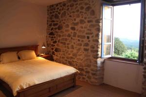 ein Schlafzimmer mit einem Bett und einem großen Fenster in der Unterkunft Les Chardons Bleus in Saint-Laurent-sous-Coiron