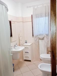 a white bathroom with a sink and a toilet at La Casa di Rossella nel cuore della città , Downtown spacious apartment in Olbia