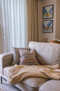 a living room with a couch with pillows on it at Modern 1-Bedroom Retreat with 35sqm Terrace, Overlooking Rudaki Park, City Skyline and Mountain Views in Dushanbe