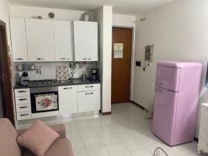 een keuken met een roze koelkast en witte kasten bij Appartamento Eleonora in Sirmione