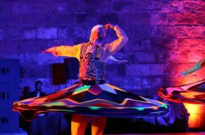 a man in a colorful dress dancing on a stage at Arobab desert safaris in Ajman 