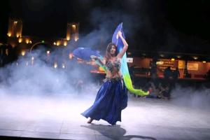 a woman in a blue dress dancing on a stage at Arobab desert safaris in Ajman  +17 photos