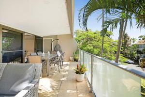 a balcony with a table and chairs and palm trees at Noosasoon - Central Family Friendly Holiday Apt with Pool in Noosa Heads