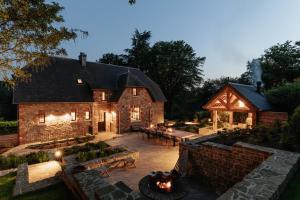 an exterior view of a stone house with a fire pit at Le Temps de Vivre Chimay - Ardennen in Momignies