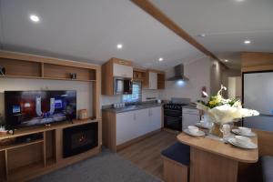 eine große Küche mit einem Tisch und einem TV in der Unterkunft 25 Poplars Way Walton on Naze in Walton-on-the-Naze