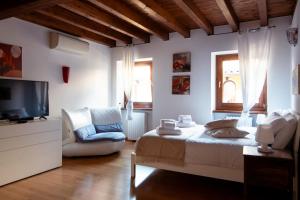 a bedroom with a bed and a tv and a chair at Casa agli Archi in Bardolino