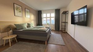 a bedroom with a bed and a flat screen tv at Aura - Nulandt#3 - 2 Zimmer, 4 Betten, Küche, Balkon, Waschmaschine in Merseburg
