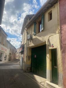 a building with green doors on the side of a street at Gîte climatisé proche lac et Mer avec accès jacuzzi en sus in Vauvert
