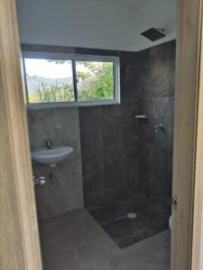 ein Badezimmer mit Waschbecken und Dusche mit Fenster in der Unterkunft VILLA TOPOCORO HiDROSOGAMOSO in San Vicente de Chucurí