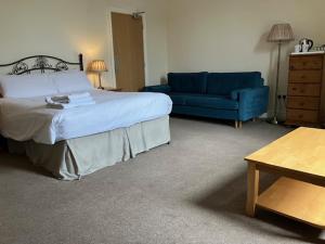 a bedroom with a bed and a blue couch at Fair Oak House Exeter Airport in Exeter