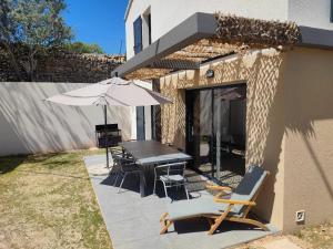 Un patio con una mesa y sillas y una sombrilla. en Villa Escale Marine, Vue Mer, 3 chambres - 2 lits double et 2 lits simples, en La Ciotat