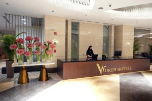 Eine Frau sitzt an einem Rezeptionstresen in der Hotellobby in der Unterkunft Peninsula Worth Hotel in Medina