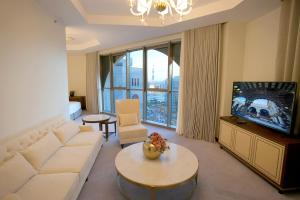 a living room with a white couch and a tv at Peninsula Worth Hotel in Al Madinah