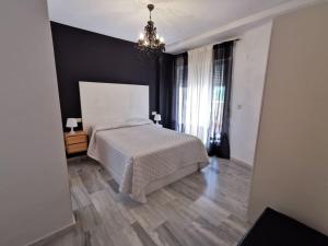 a bedroom with a white bed and a chandelier at Apartamento Vigar in Castell de Ferro