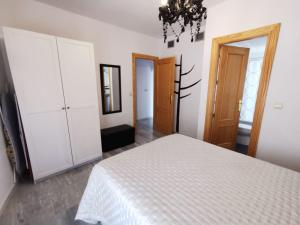 a bedroom with a white bed and a chandelier at Apartamento Vigar in Castell de Ferro