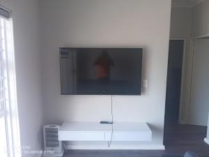 Un televisor de pantalla plana colgado en una pared blanca en Muizenberg Magic OceanfrontOasis, en Marina da Gama