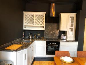 a kitchen with white cabinets and a black wall at The Residence Sasco Apartments in Blackpool +20 photos