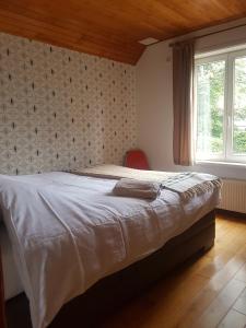 フーフェルラントにあるAppartement met terras 2 - 8 gasten Heuvelland Rodebergのベッドルーム1室(ベッド1台、赤い椅子、窓付)