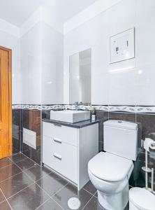 Un baño blanco con inodoro y lavabo. en Casa da Abegoaria, en Caniço
