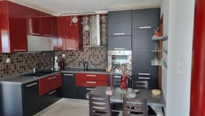 a kitchen with red cabinets and a table with chairs at Coastal maisonette in Nea Potidaea +15 photos