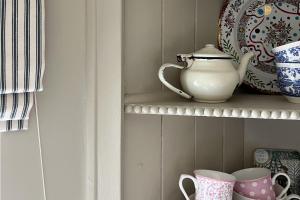 - une étagère avec une théière et des tasses dans l'établissement Worstead Cottage by Big Skies Cottages, à Worstead