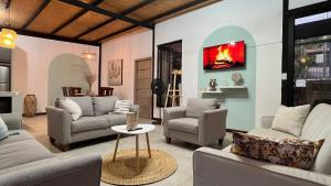 a living room with couches and chairs and a tv at Casa-Refugio Del Sol in Vilcabamba