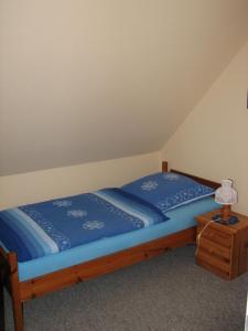 a bedroom with a bed with a blue comforter and a lamp at Ferienwohnungen Langholz in Hohn