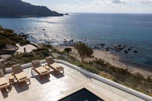 a balcony with chairs and a view of the ocean at Rokkea Villa in Plakias