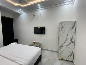 拉合尔Hotel Day IN Shoukat khanam的一间卧室，墙上有一张床和一台电视
