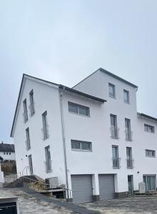 a large white building with two garage at Neubau Donaublickapartments in Sinzing