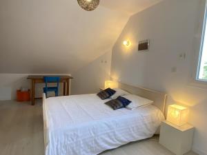 a bedroom with a white bed with two pillows at La Clairière in Jullouville-les-Pins